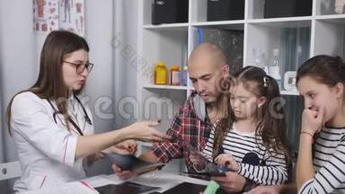 父亲带着两个女儿在<strong>家庭医生</strong>办公室咨询。 女<strong>医生</strong>和父亲谈话